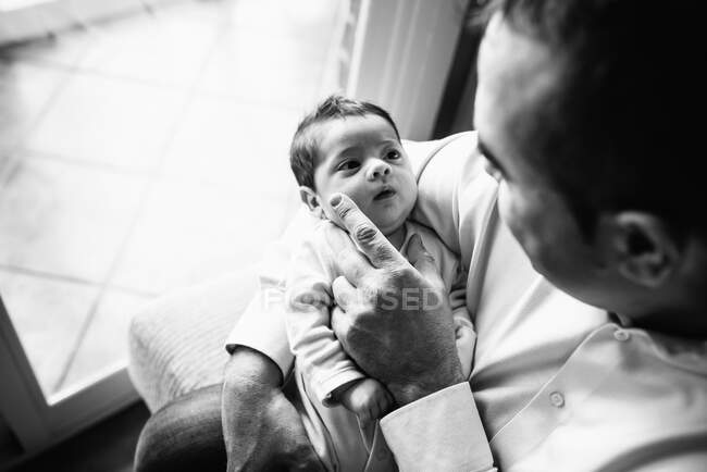 Padre abrazando lindo bebé mirando hacia otro lado en casa - foto de stock