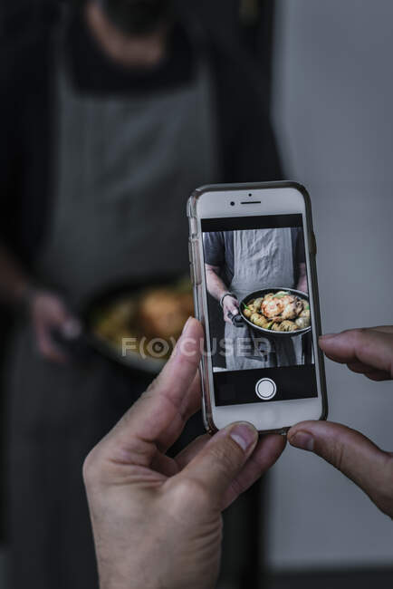 Persona de la cosecha toma de fotos a mano en el teléfono móvil sabroso plato en las manos del hombre sin rostro - foto de stock