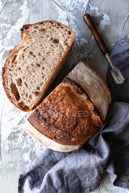 From above homemade fresh sourdough bread in tablecloth on wooden table — Stock Photo