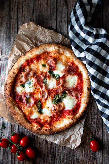 Leckere Pizza mit Tomaten und Rucola auf rustikalem Holzgrund — Stockfoto
