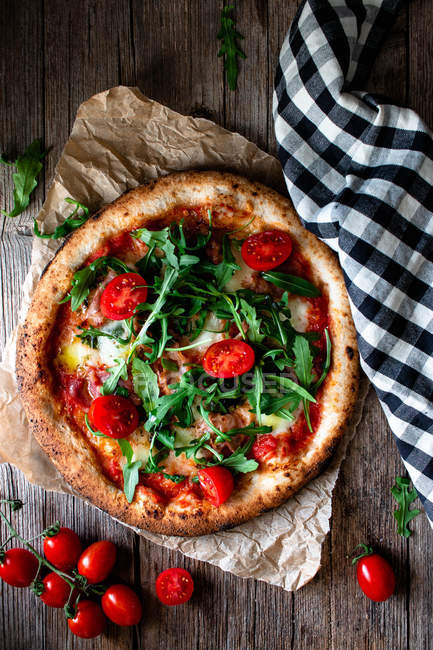 Deliciosa pizza com tomates, rúcula e mussarela em fundo de madeira rústica — Fotografia de Stock