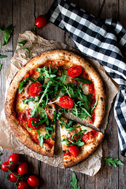Delicious pizza with tomatoes, arugula and mozzarella on rustic wooden background — Stock Photo