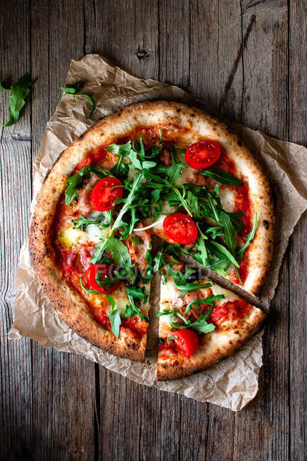 Deliciosa pizza con tomates, rúcula y mozzarella sobre fondo rústico de madera - foto de stock