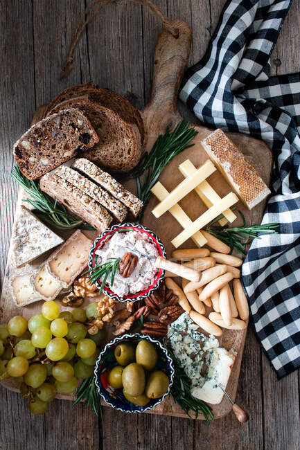 From above composition of fresh rye bread, cheese, grape bunch and olives placed on wooden board — Stock Photo