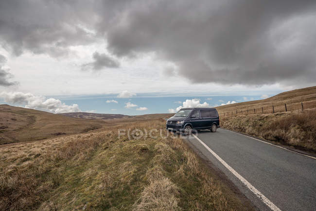 Automobile on asphalt road in mountain terrain in sunny day in Wales — Stock Photo