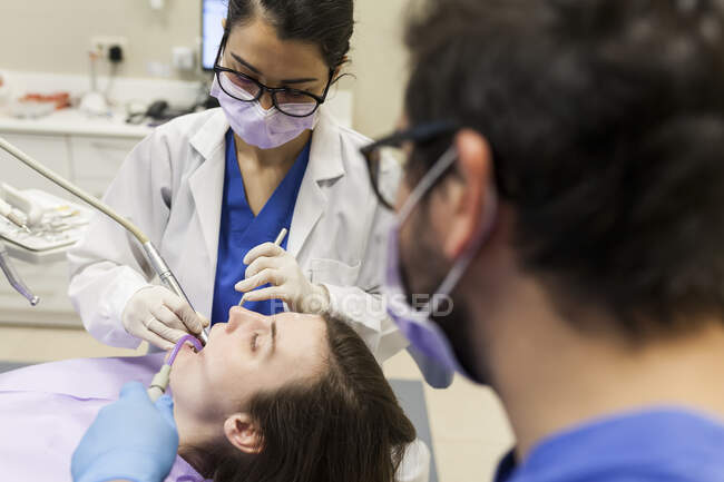 Жінка-стоматолог, яка відвідує пацієнта зі своїм помічником — стокове фото