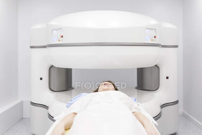 Mujer de mediana edad en una máquina de resonancia magnética abierta esperando a que comience la prueba - foto de stock