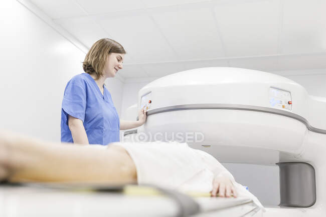 Mujer de mediana edad y su médico en una máquina de resonancia magnética abierta esperando a que comience la prueba - foto de stock