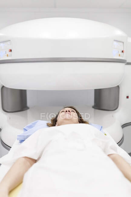 Femme d'âge moyen sur une machine ouverte d'IRM attendant que le test commence — Photo de stock