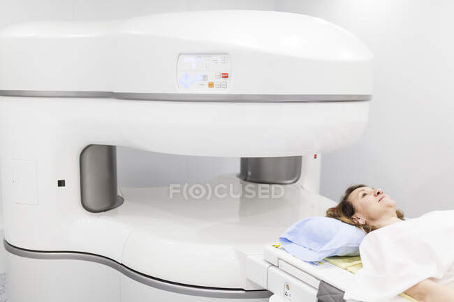 Femme d'âge moyen sur une machine ouverte d'IRM attendant que le test commence — Photo de stock