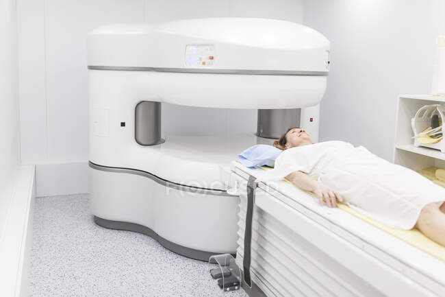 Mujer de mediana edad en una máquina de resonancia magnética abierta esperando a que comience la prueba - foto de stock