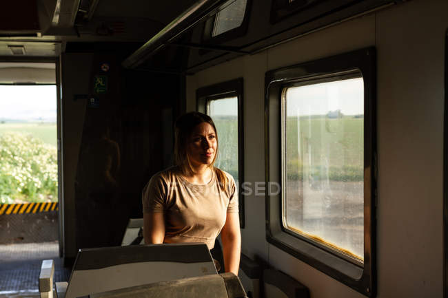 Mujer soldado mirando por la ventana mientras viaja por el campo en vehículo militar - foto de stock