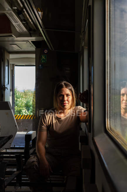 Soldado feminino olhando para a câmera enquanto viaja pelo campo em veículo militar — Fotografia de Stock