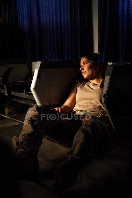 Sério militar mulher de uniforme olhando para longe enquanto sentado no chão do transporte do exército — Fotografia de Stock