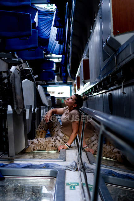 Приваблива жінка-солдат, яка дивиться вгору, сидячи всередині сучасного військового транспорту — стокове фото