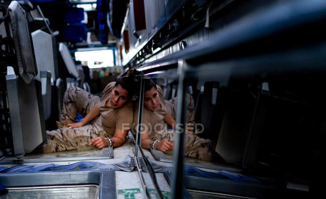 Soldat féminin regardant la caméra allongée sur le sol du transport militaire contemporain — Photo de stock