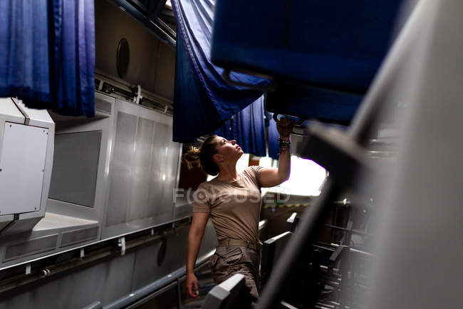Soldado feminino atraente olhando para cima enquanto estava dentro do transporte militar moderno — Fotografia de Stock