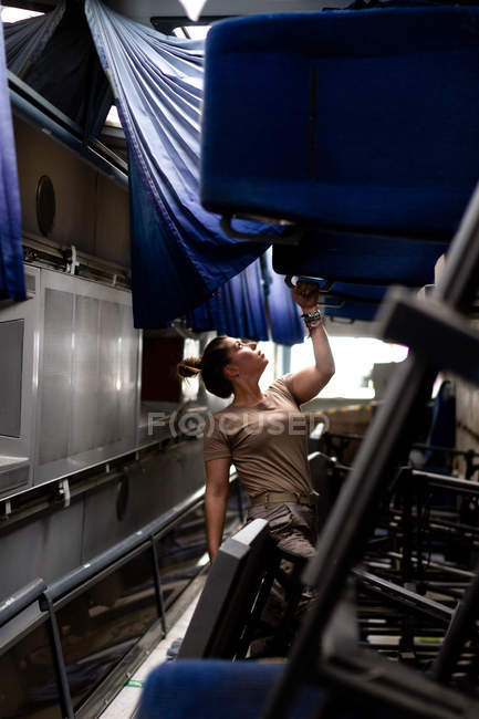 Attractive female soldier looking up while standing inside modern military transport — Stock Photo