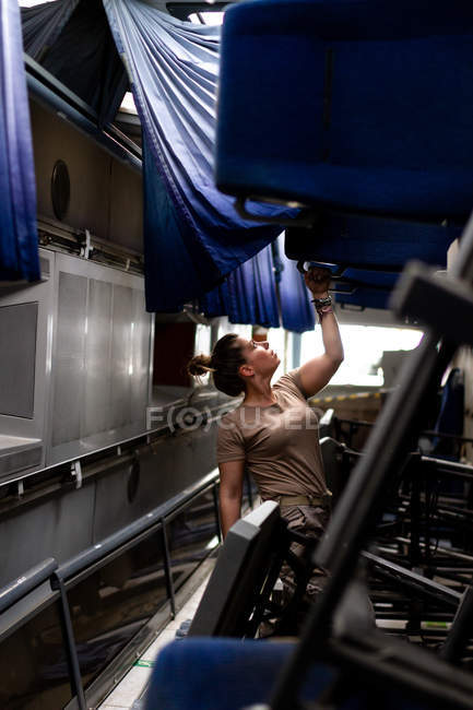 Atractiva soldado mujer mirando hacia arriba mientras está de pie dentro del transporte militar moderno - foto de stock
