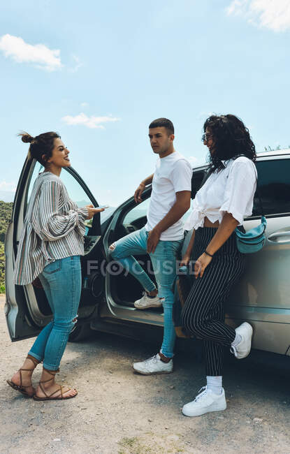 Группа друзей наслаждается беседой за дверью машины. Они говорят и селфи в туристическом месте — стоковое фото