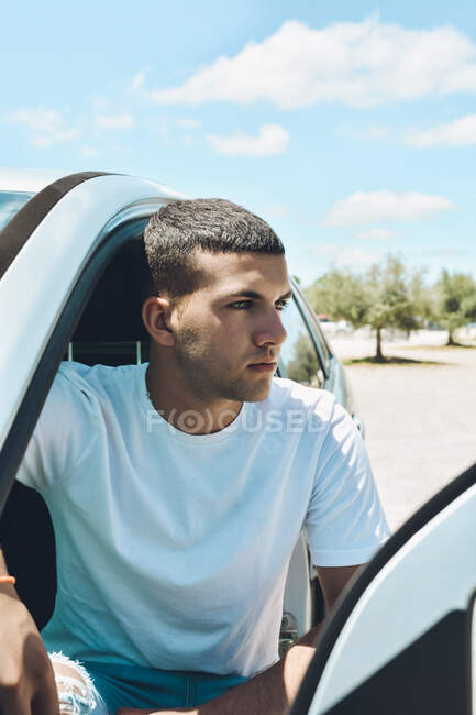 Молодий блакитноокий чоловік і сучасний одяг вилітають зі своєї машини — стокове фото