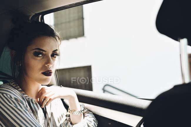 Портрет красивой девушки, сидящей в автомобильном кресле, когда на ее лице солнечные лучи. — стоковое фото