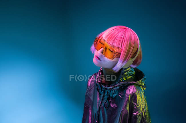 Молодая азиатка со стильной розовой стрижкой и блестящей серебряной курткой стоя и наслаждаясь музыкой — стоковое фото