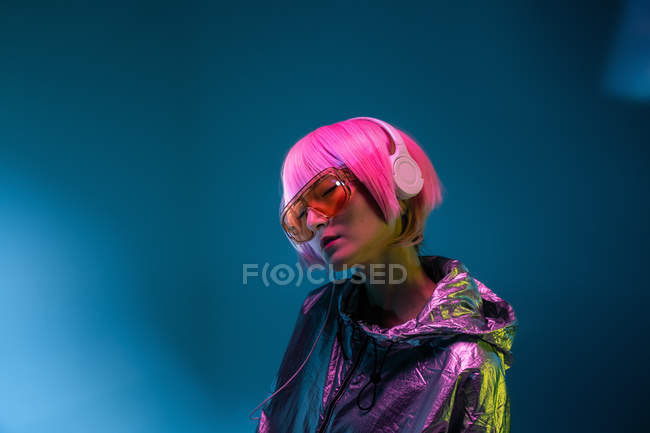 Молода Азіатська жінка зі стильною рожевої стрижки і блискучий Срібний піджак стоячи і насолоджуючись музикою — стокове фото