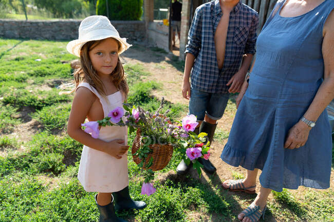 Seniorin und Enkelinnen pflücken an sonnigem Tag auf Bauernhof gemeinsam schöne Blumen im Garten — Stockfoto