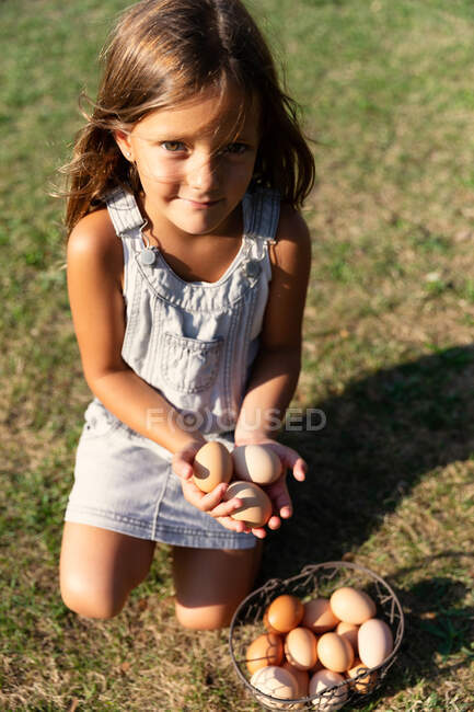 Kleines Mädchen mit Eierkorb auf Bauernhof und Blick in die Kamera — Stockfoto