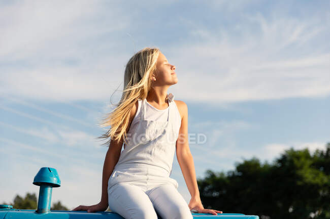 Little girl sitting on tractor against cloudy sky on farm — Stock Photo