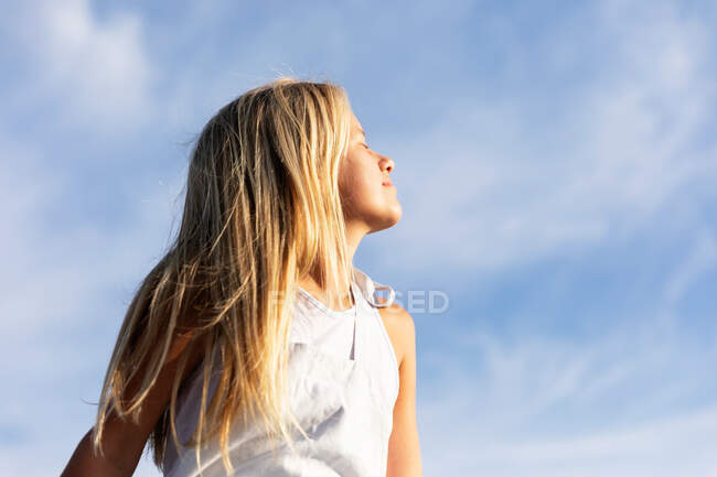 Молода дівчина позує на сонячному світлі, дивлячись далеко — стокове фото