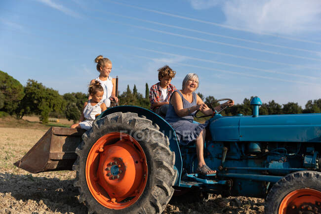 Ältere Frau fährt Traktor bei Feldarbeiten am sonnigen Tag auf Bauernhof — Stockfoto