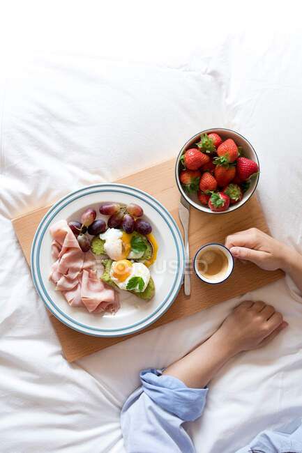 De cima vista da cultura de mulher anônima tomando um saboroso pequeno-almoço nutritivo apetitoso servido na cama — Fotografia de Stock