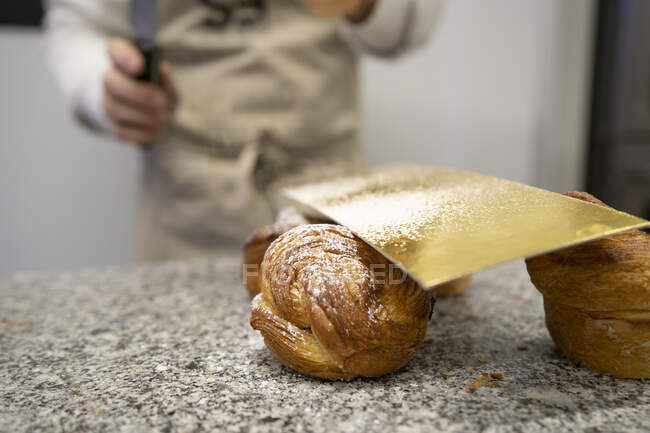 De arriba hombre de la cosecha en delantal sumergiendo crujientes croissants en un tazón con deliciosa crema de chocolate - foto de stock