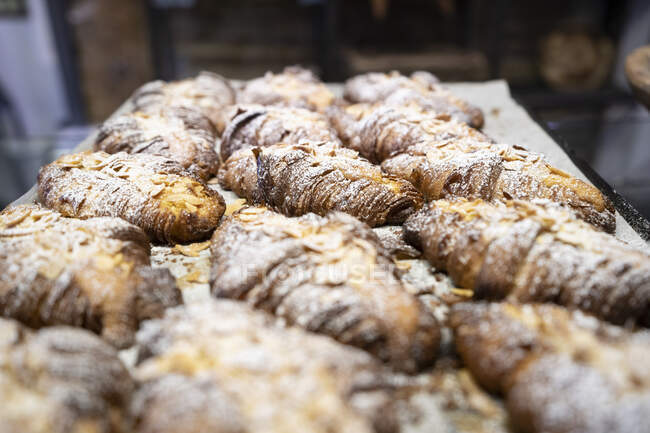 From above composition of freshly baked French croissants with sliced almonds and sugar powder — Stock Photo