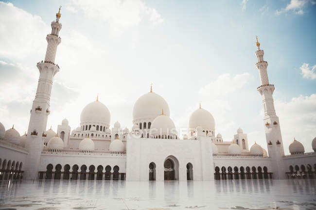 Exterior of white mosque with domes and minarets under bright blue sky, Dubai — Stock Photo