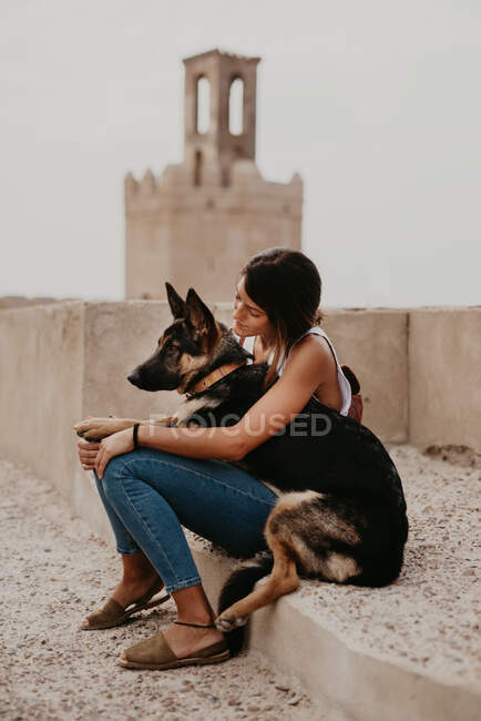 Casual young women sitting on concrete pavement with adorable german shepherd — Stock Photo
