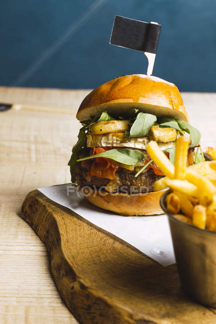 Juicy delicious burger and fried potato on wooden board — Stock Photo