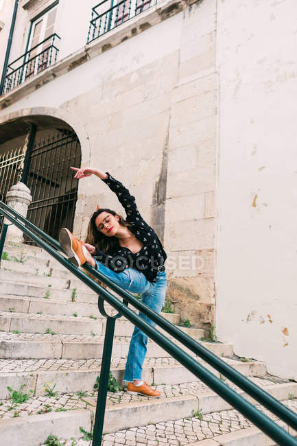 Молодая стройная случайная женщина растягивается и танцует на лестнице, грациозно танцуя на улице старого города — стоковое фото