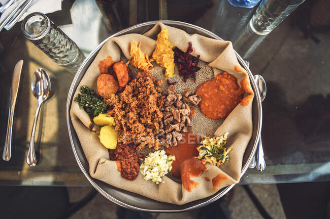 Plato etíope tradicional de Injera con pan plano y verduras variadas servidas en la mesa - foto de stock