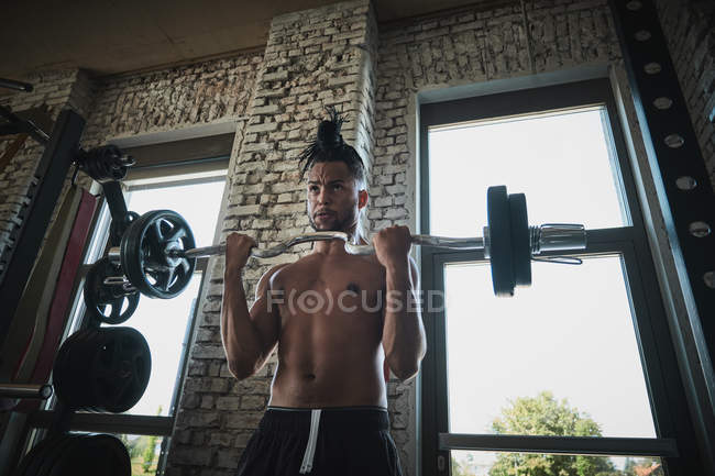 Hombre negro que hace ejercicio con campana en el gimnasio - foto de stock
