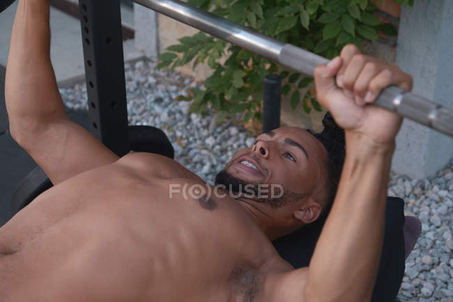 Black guy lifting barbell on street — Stock Photo