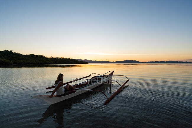 Woman in boat admiring lake at sunset — Fotografia de Stock