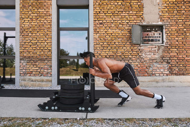 Black guy tirando pesos en el gimnasio al aire libre - foto de stock