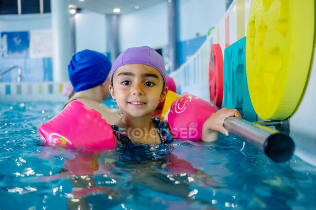 Chica étnica con alas de agua en la piscina - foto de stock