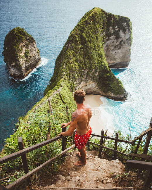Людина на краю над тропічним узбережжям зі скелями — стокове фото