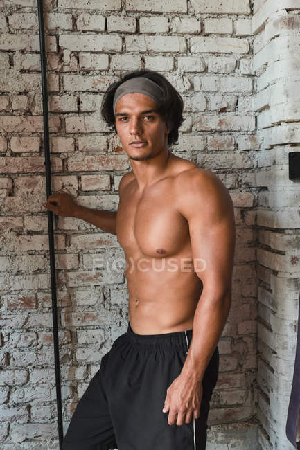 Un hombre musculoso joven que se pone en el gimnasio - foto de stock