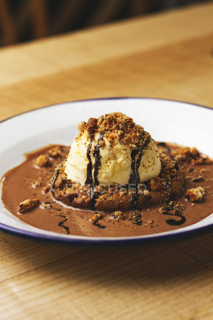 Вкусный сладкий бургер с шоколадной крошкой и орехами подается на тарелке на деревянном столе — стоковое фото