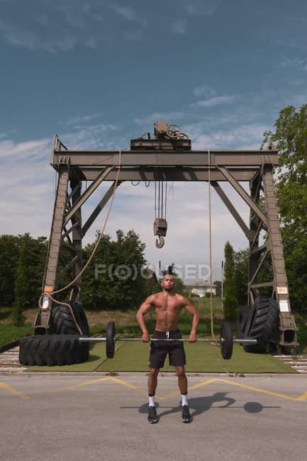 Black guy with barbell in outdoor gym — Stock Photo